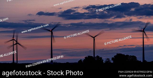 24 September 2022, Mecklenburg-Western Pomerania, Mühlen Eichsen: Wind turbines turn before sunrise and are marked by red warning lights
