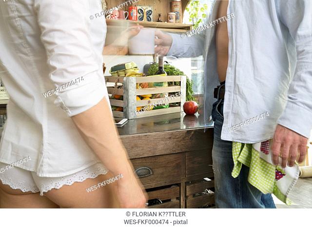 Couple in kitchen with crate of groceries on counter