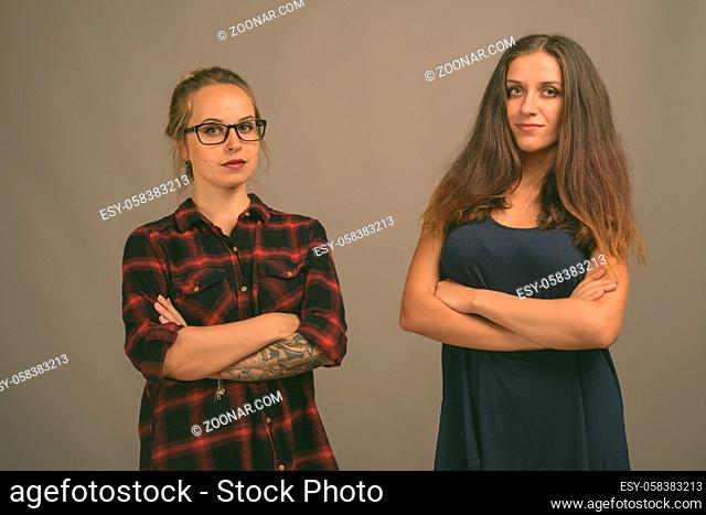 Studio shot of two young beautiful woman friends together against gray background