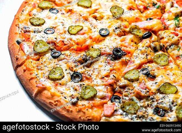 pizza with sausage and pickles, by cut to pieces on a metal table. selective focus on the filling close-up