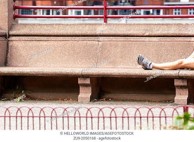 Male runner lying on bench with leg outstretched