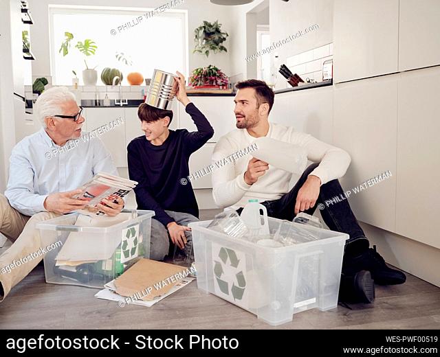 Grandfather, father and son having fun separating waste into recycling boxes