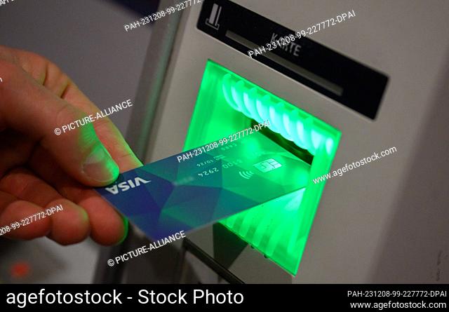 08 December 2023, Lower Saxony, Hanover: A VISA debit card is held in front of an ATM at a press conference in Hanover City Hall (staged scene)