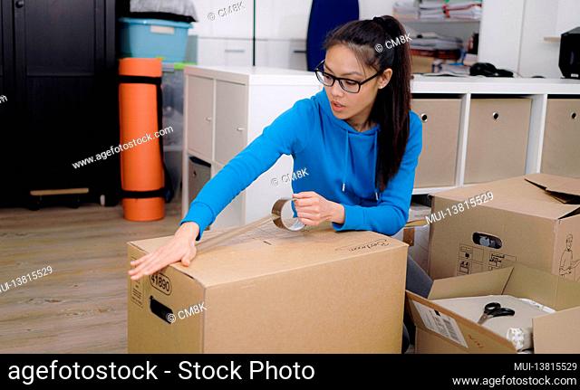 Young woman packs a cardboard box for the move