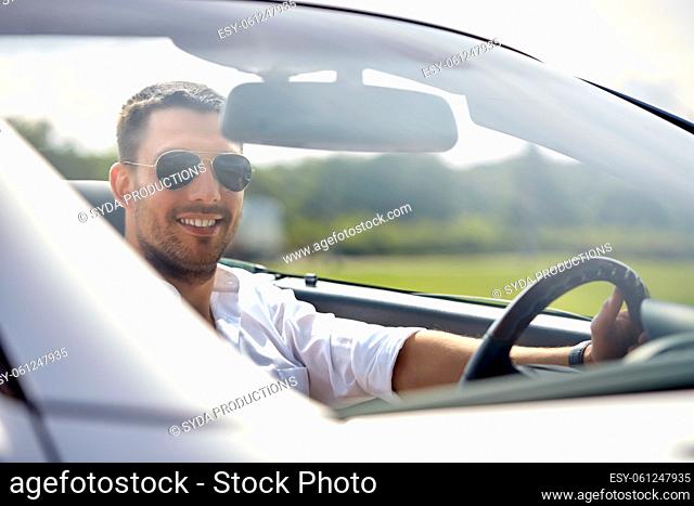 happy man in sunglasses driving convertible car