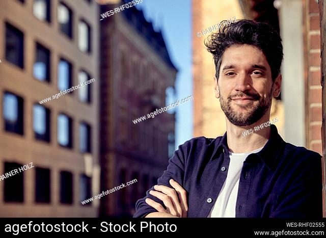 Businessman smiling while leaning on wall