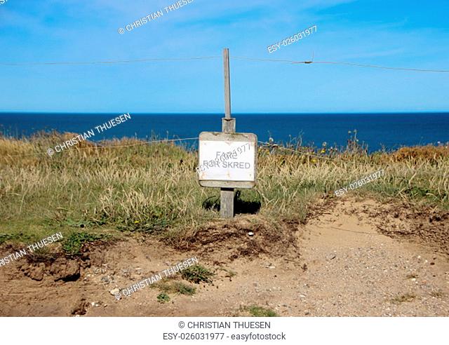 Danish Sign at Edge of Cliff warning of Earth Erosion