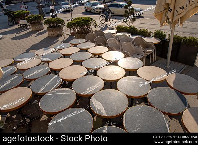 25 March 2020, Bavaria, Munich: Coffee house tables are set close together in front of a café on Odeonsplatz. Photo: Peter Kneffel/dpa