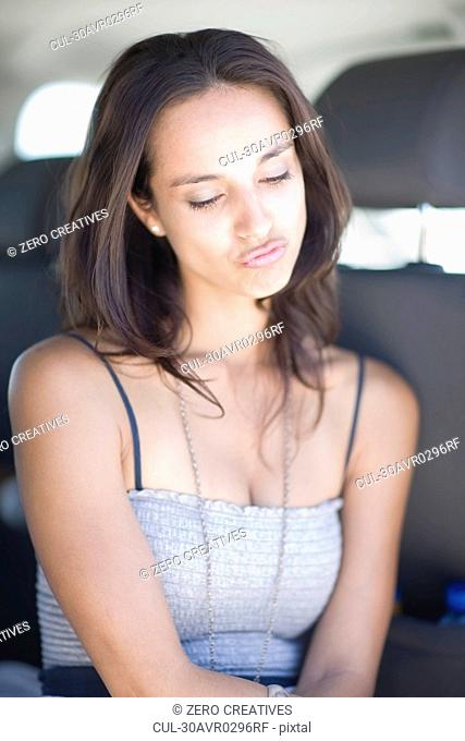 Offended young woman sitting in car