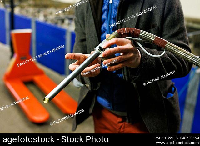 17 December 2021, France, Bischoffsheim: Gilbert Schmitt holds the tube of a stuffing machine for ducks in his hand. The machine is used to stuff ducks or geese...