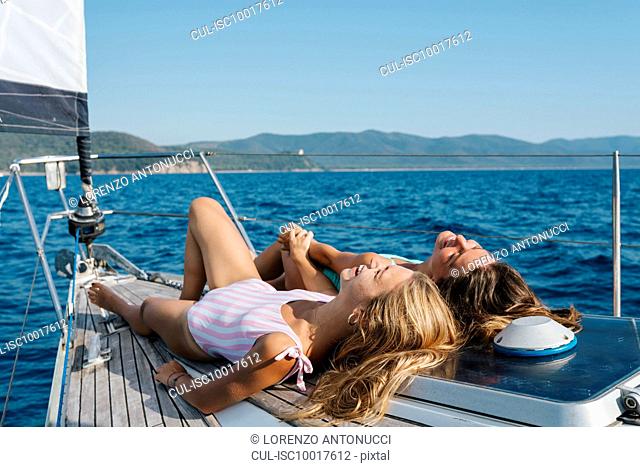 Friends sunbathing on deck of sailboat, Italy