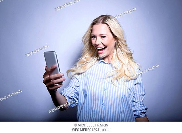 Portrait of happy blond woman looking at smartphone