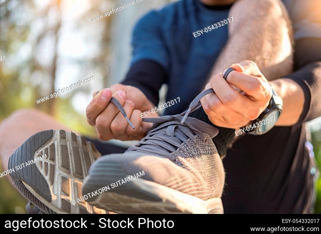 Male athlete tying shoe laces in minimalistic barefoot sneakers getting ready for training. Sport workout and healthy lifestyle concept