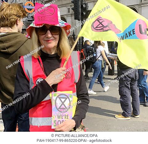 17 April 2019, Great Britain, London: Jenn Parkhouse of the Extinction Rebellion movement is waving a yellow flag with the words ""Wake"" during the...