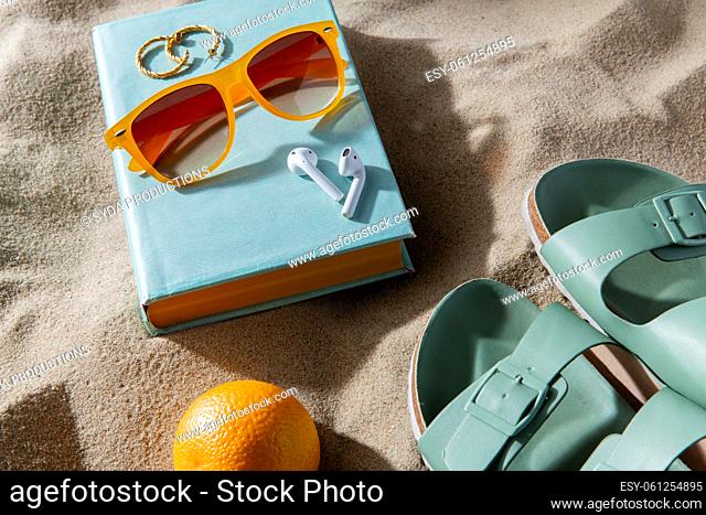 slippers, orange, earbuds and sunglasses on beach