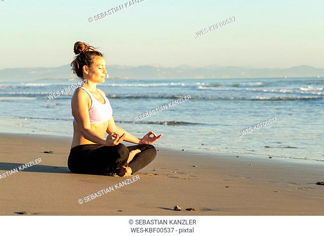 Woman meditating on the beach in the evening