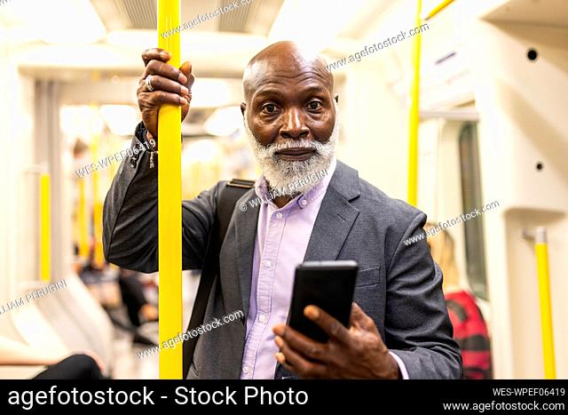 Senior passenger with smart phone in subway train