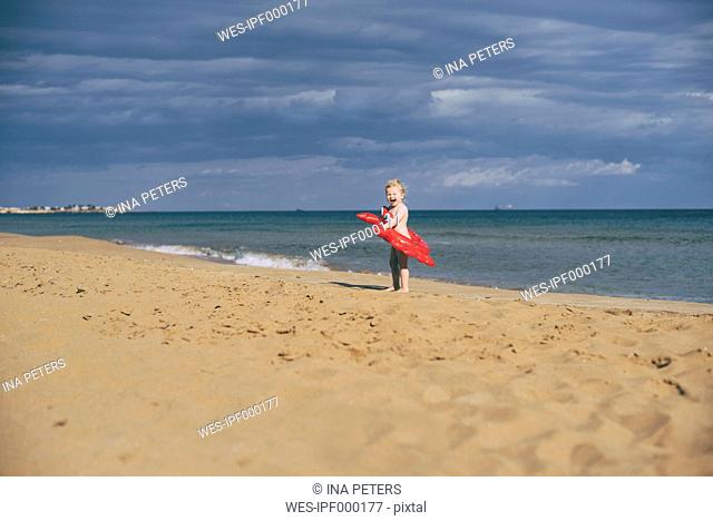 Sicily, Syracuse, Noto, girl with red crab swim toy at the beach