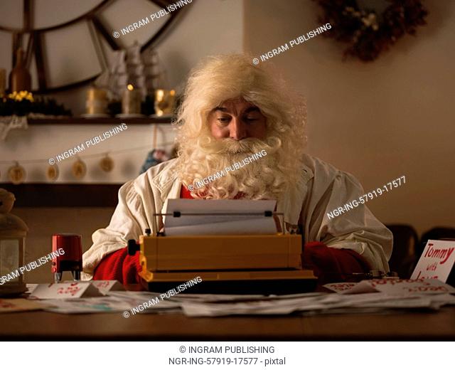 Santa Claus Working at Home. Reading and Writing letters for Children on Typewriter