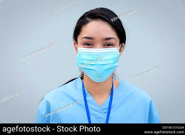 Portrait of female health professional wearing face mask against grey background