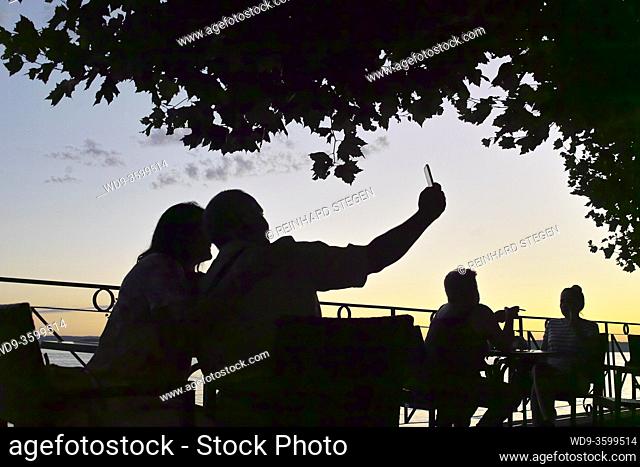 couple taking selfie by lake at sunset