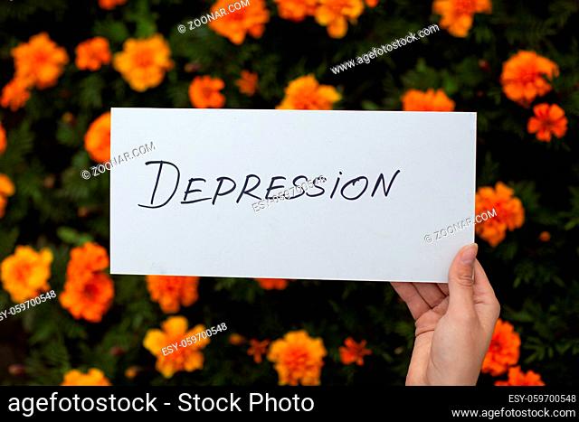 Woman holds in hand white sheet of paper with the word Depression on flower background