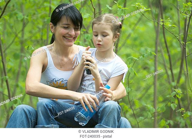 Mother and daughter sitting together in forest