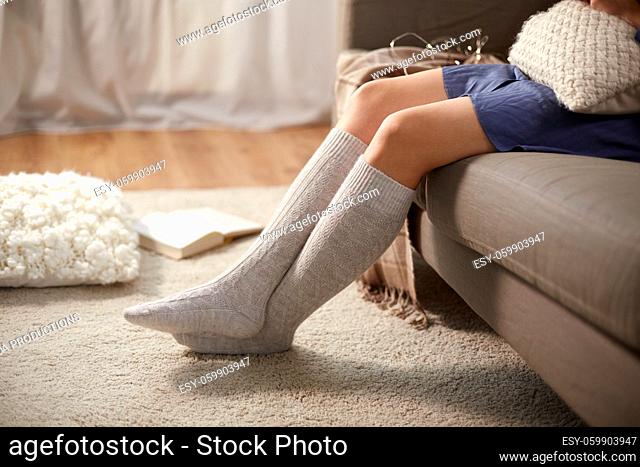 woman in socks with pillow sitting on sofa at home