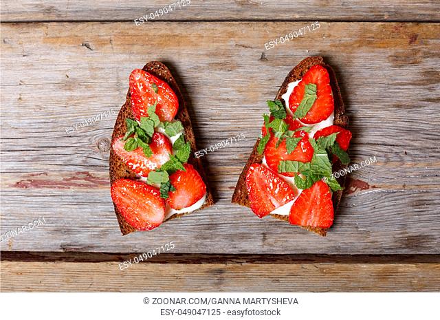 Vegetarian food. Two sandwiches with strawberries, sour cream and mint on a wooden background. snack
