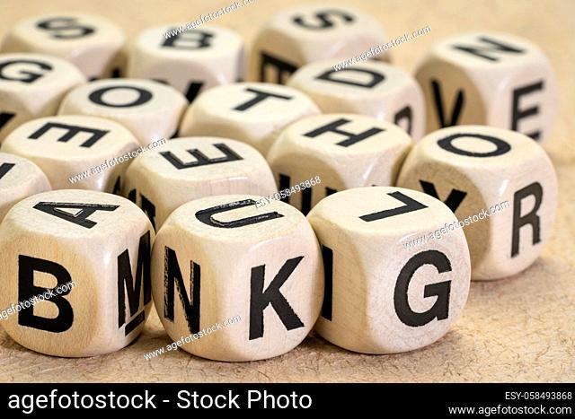 alphabet abstract in wooden letter cubes against textured paper, language and communication concept