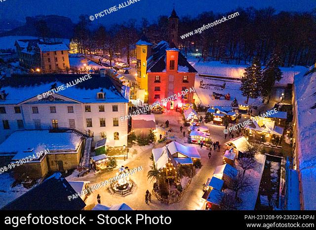 08 December 2023, Saxony, Königstein: The stalls at the Christmas market at Königstein Fortress are brightly lit (aerial view taken with a drone)