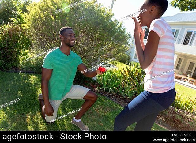 African american couple on sunny garden terrace a man proposing to her