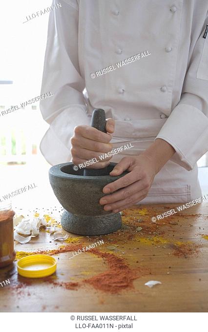 Chef Using Mortar and Pestle to Grind Together Garlic, Marsala and Tumeric  KwaZulu Natal Province, South Africa