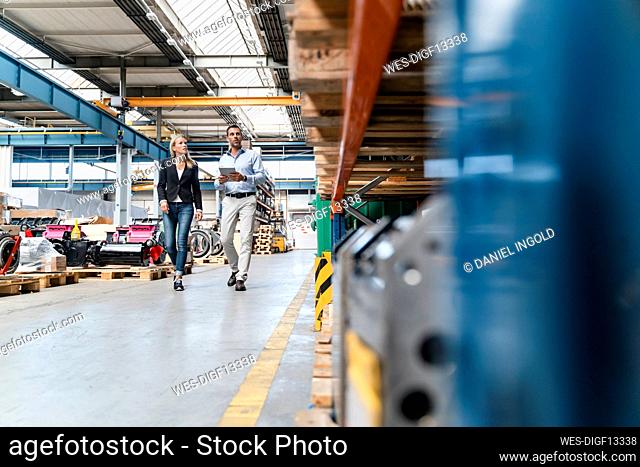 Businessman and female colleagues with digital tablet while walking in industry