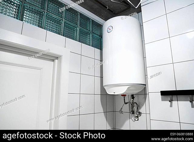Household budget water heater hanging on the wall in boiler room. Modern gas tanked boiler in bathroom. ?ommon electric storage tank water heater