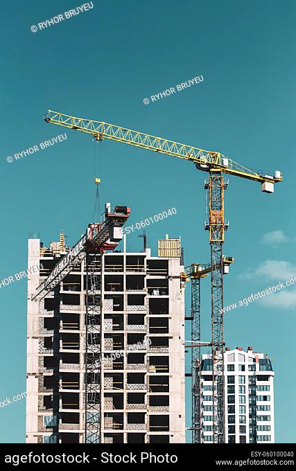 Construction Crane Is Involved In The Construction Of A New Multi-storey Residential Building. Sunny Summer Day. Construction Crane On Background Of Blue Sunny...