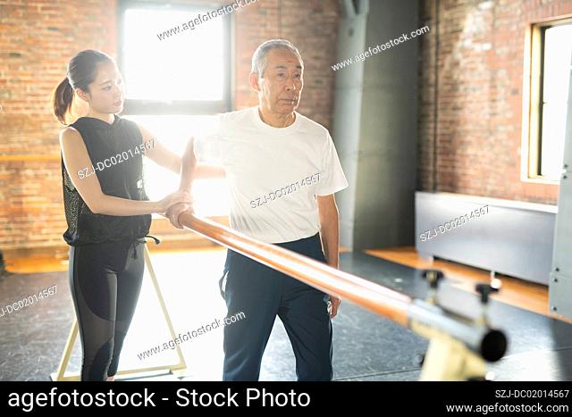 Senior man undergoing rehabilitation walking exercises with trainer