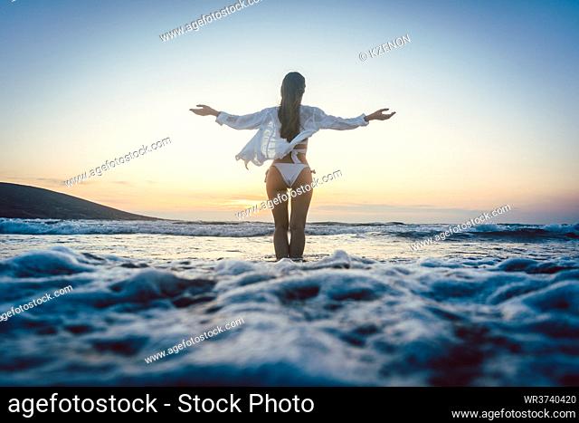 Woman enjoying the freedom of her vacation at the sea in a sunset mood