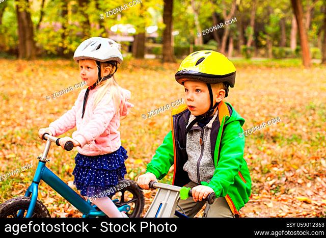 Portrait of screaming preschool girl in protective helmet riding balance bike outdoors at the park. Active and fearless girl is a young leader