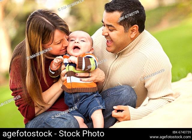 Happy mixed-race parents playing with their giggling son