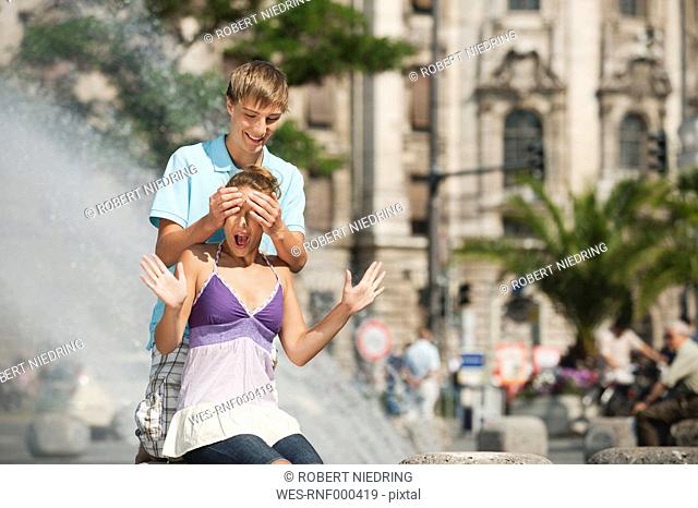 Germany, Munich, Karlsplatz, Young man covering eyes of woman