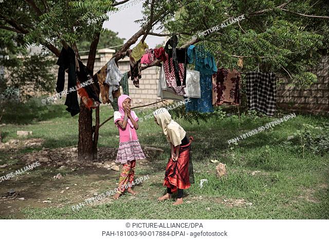26 September 2018, Yemen, Hodeida: Internally displaced Yemeni girls play after hanging up clothes to dry on a tree in a school