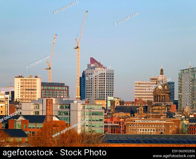 A cityscape view of leeds showing the modern buildings city hall and construction cranes