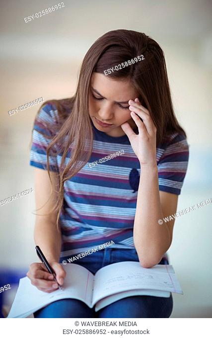 Attentive schoolgirl doing homework in classroom