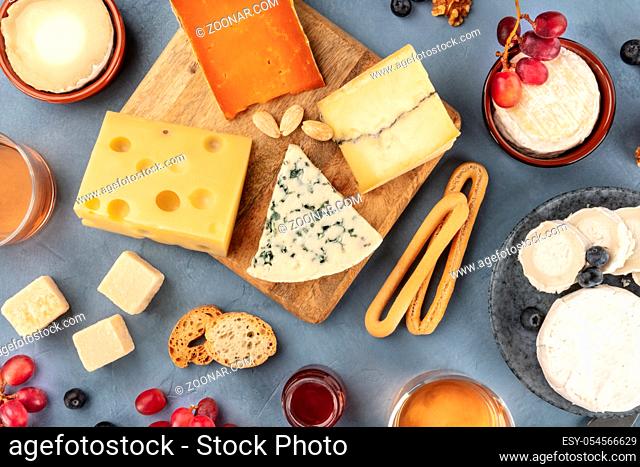 Various cheeses assortment with wine and fruit. Blue cheese, Brie, Dutch cheese and others, shot from above