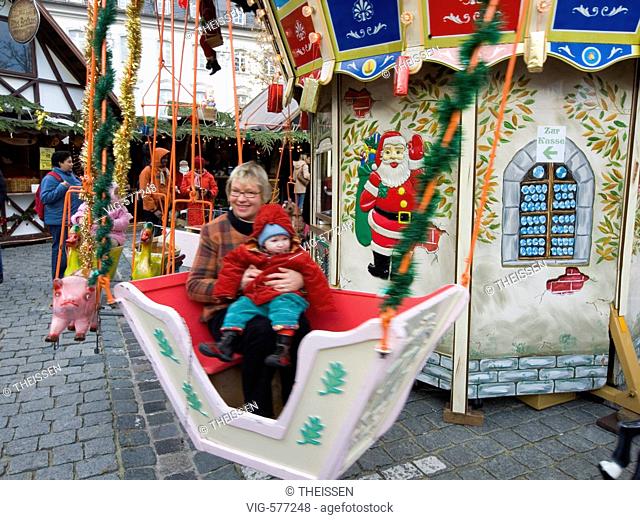 middelaged woman with a baby child sitting in a merry-go-round for little kids. - 30/11/2007