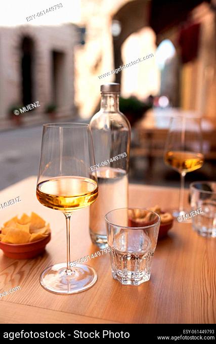 White wine and water outdoors in an mediterranean old town. Vertical holiday background with short depth of field