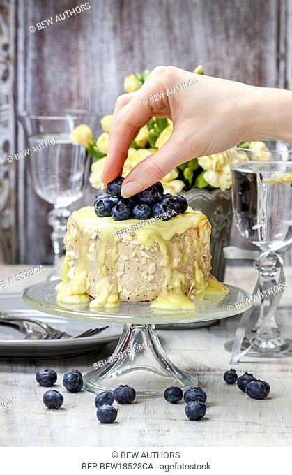 Woman decorating layer cake with ripe blueberries