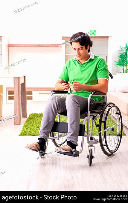 Young handsome man in wheelchair at home