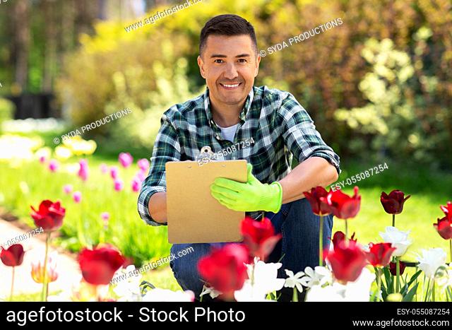 man with clipboard and flowers at summer garden